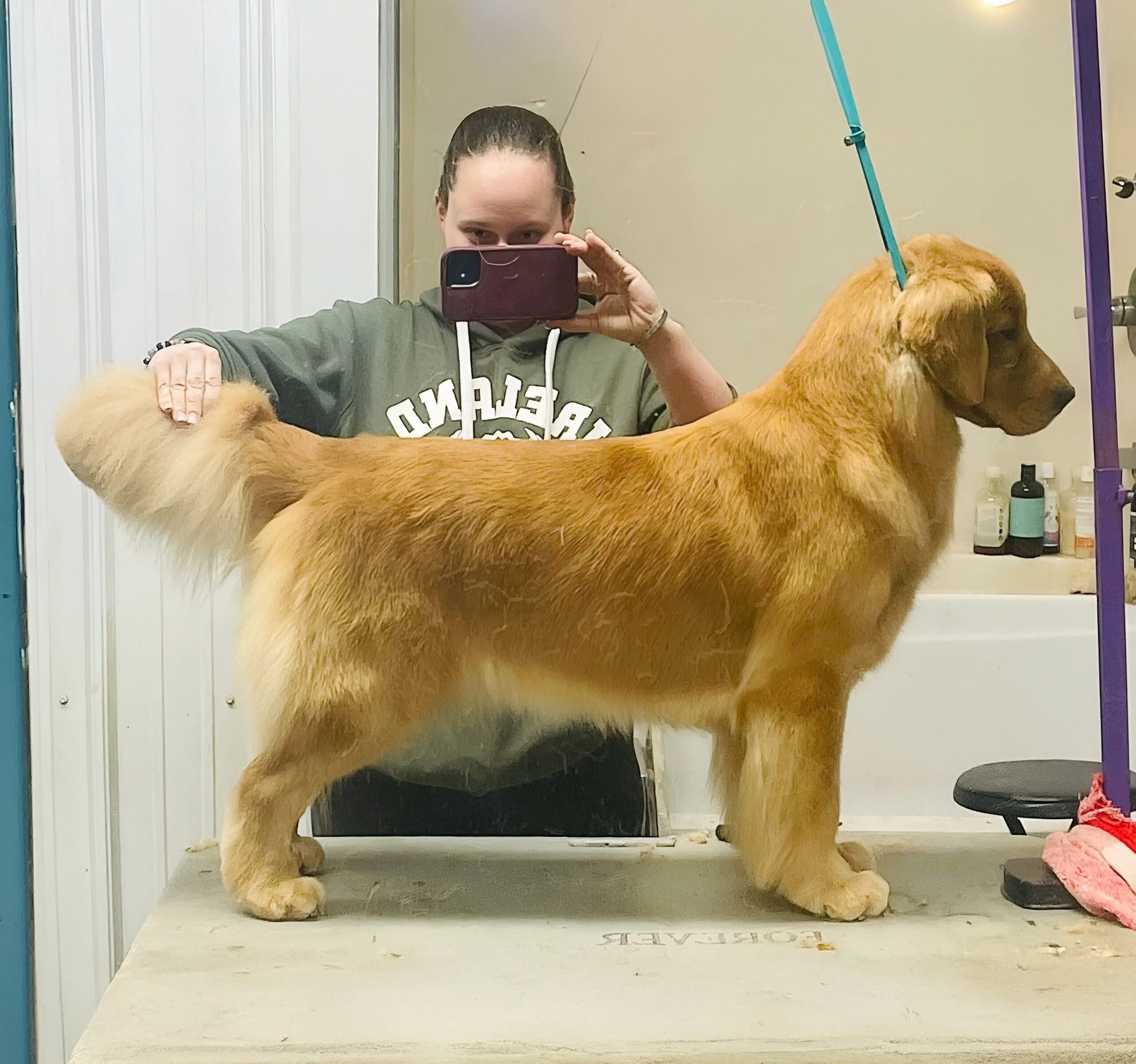 A woman takes a selfie with her dog in a bathroom, smiling at the camera with playful expressions.